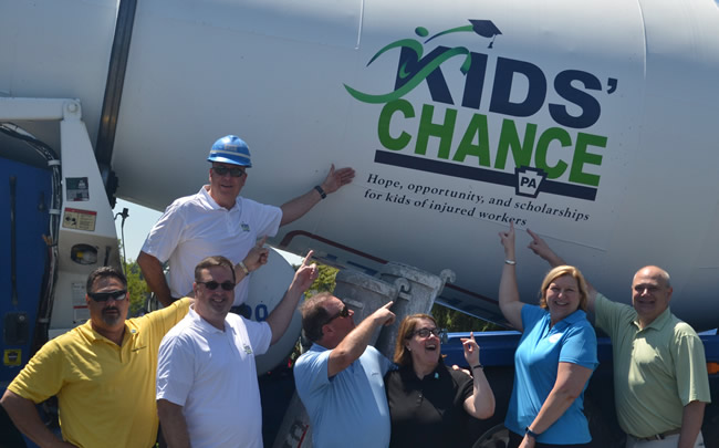 A photo of people pointing at the Kids' Chance logo on a truck.